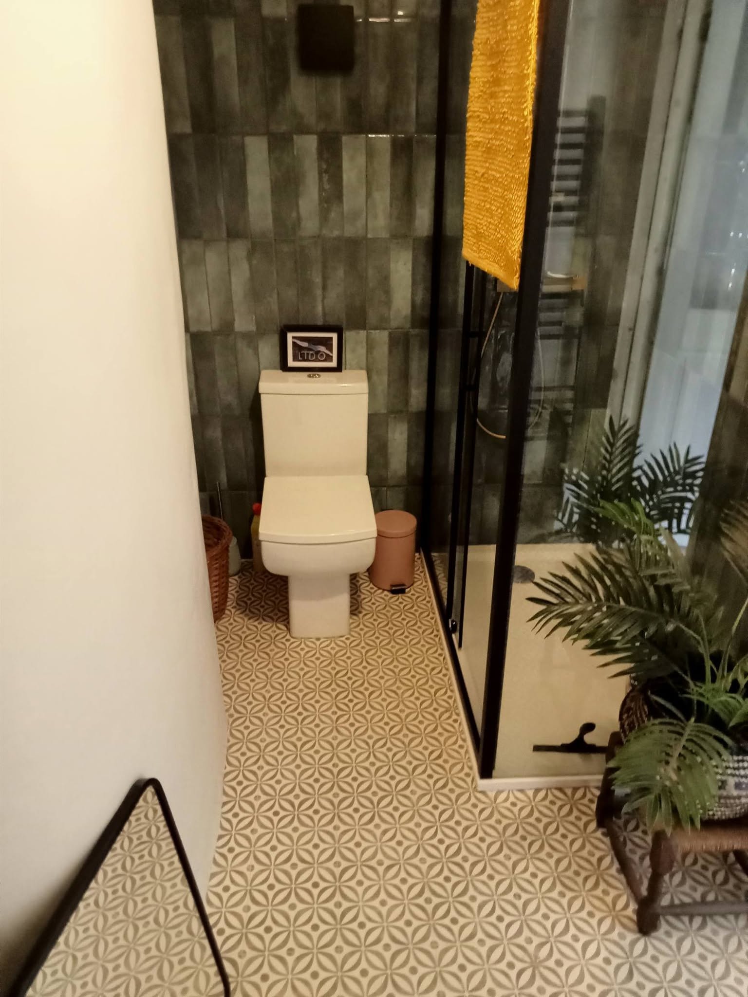 Renovated bathroom with green tiling and glass shower screen