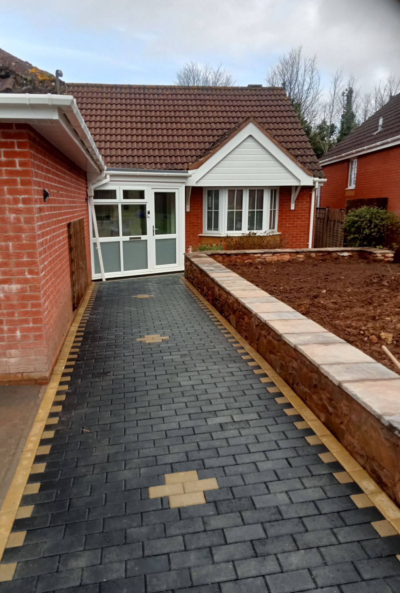 Herringbone brick paving driveway with stone retaining wall