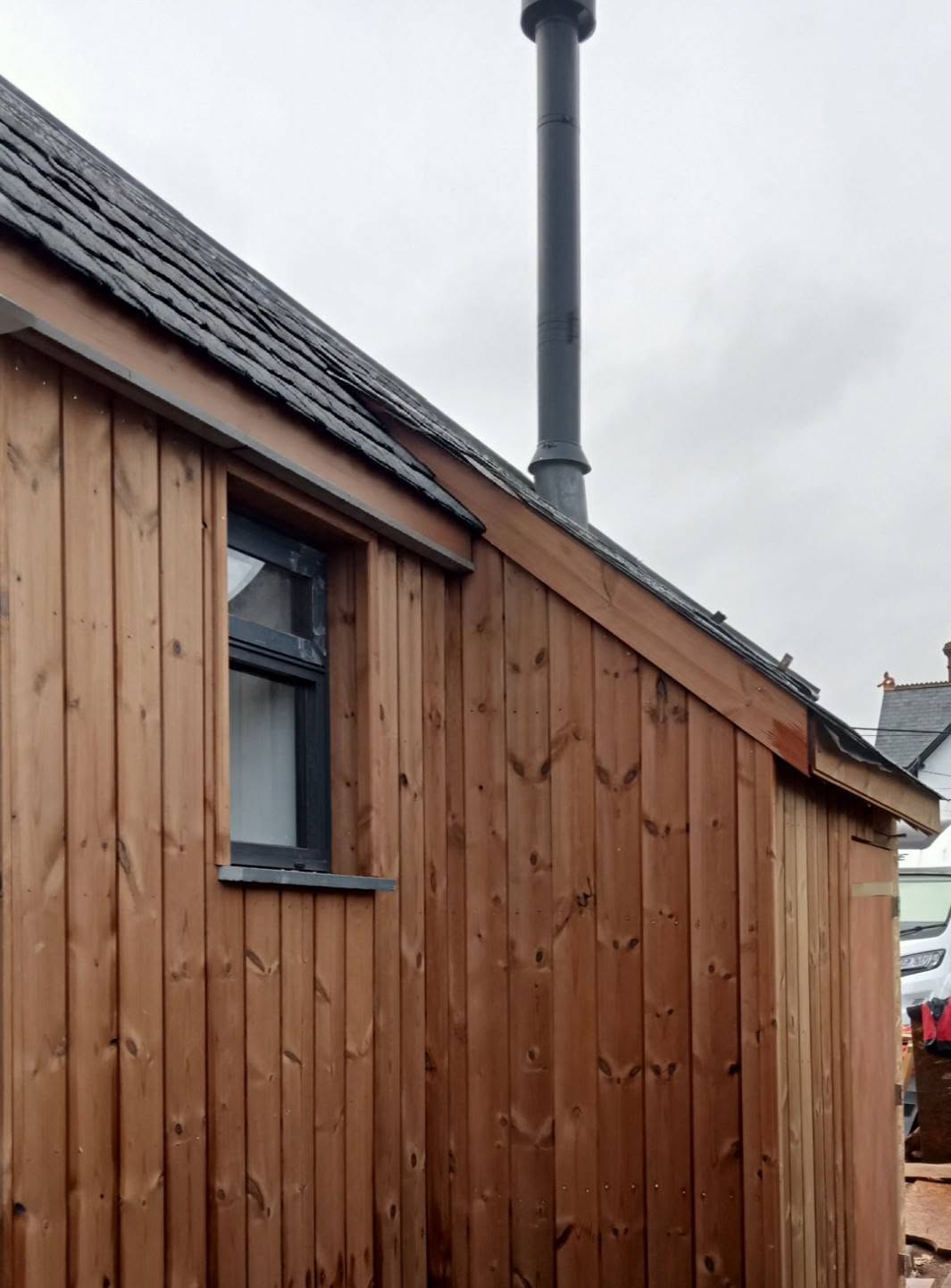 Timber cladding and slate roofline detail with flue